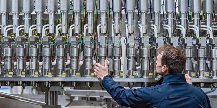 25 April 2022, Bavaria, Neutraubling: A Krones AG employee works on a filling line in production. Photo: Armin Weigel/dpa
